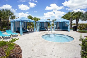 Ein Poolbereich mit Liegestühlen, einem Whirlpool und überdachten Sitzbereichen.