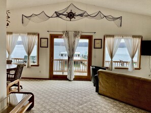 A room with a view of a lake, a wooden table with chairs, a sofa, and a door marked "EXIT". - Lake Superior View ~ Convenient ~ In town (Munising)