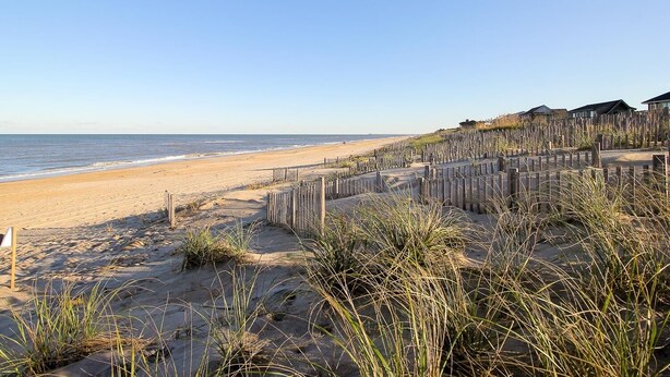 A beach with wooden structures and a clear view of the ocean. -  Serene Sanderling Beach Cottage Steps from beach w/community pool - Duck  (Duck)