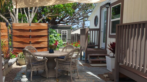 A patio area with a round table and wicker chairs, surrounded by potted plants and a wooden fence. - Fay Cottage - Convenience in the heart of La Jolla village of La Jolla (La Jolla)