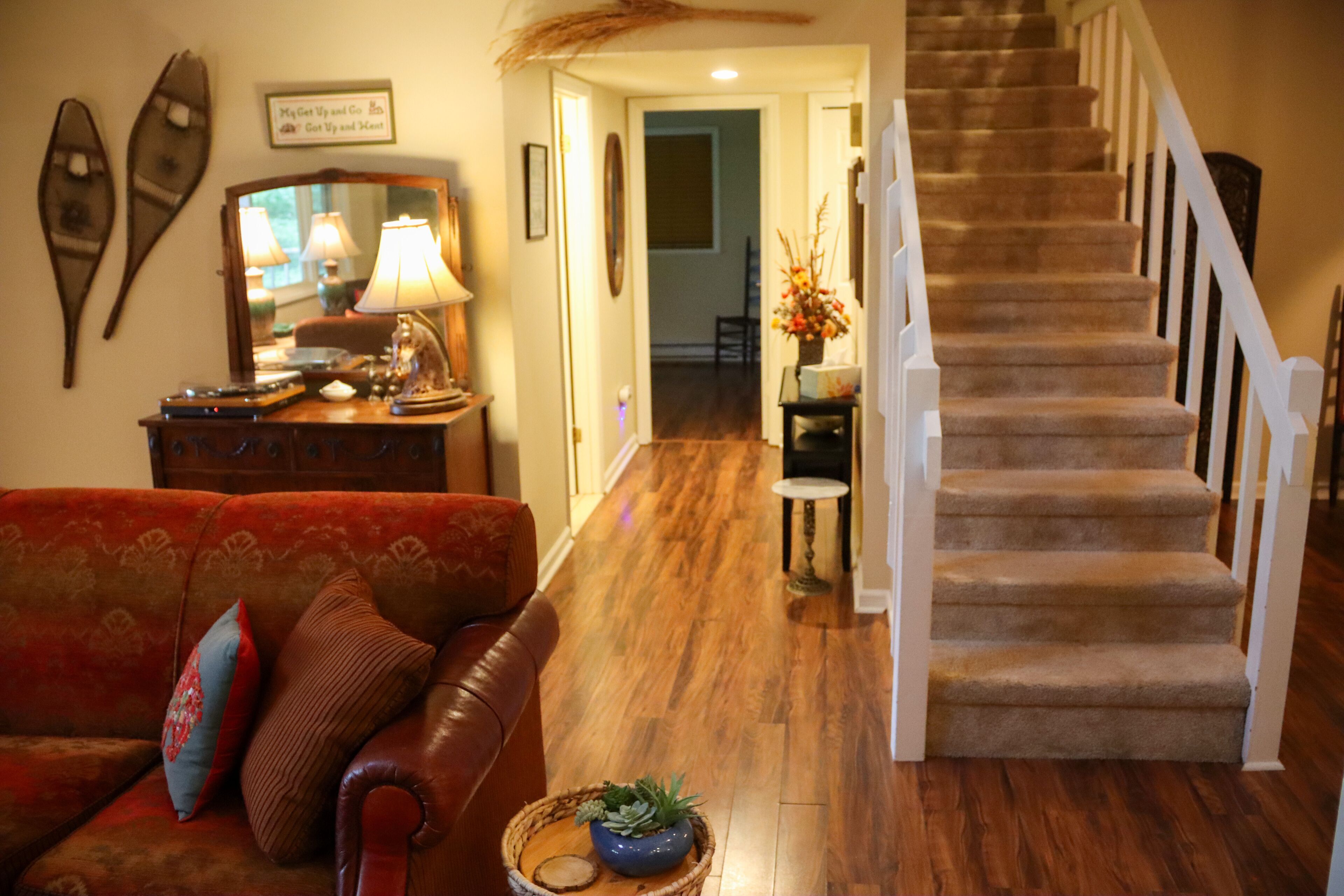A living room with a red sofa, a wooden coffee table, and a staircase with carpeted steps.