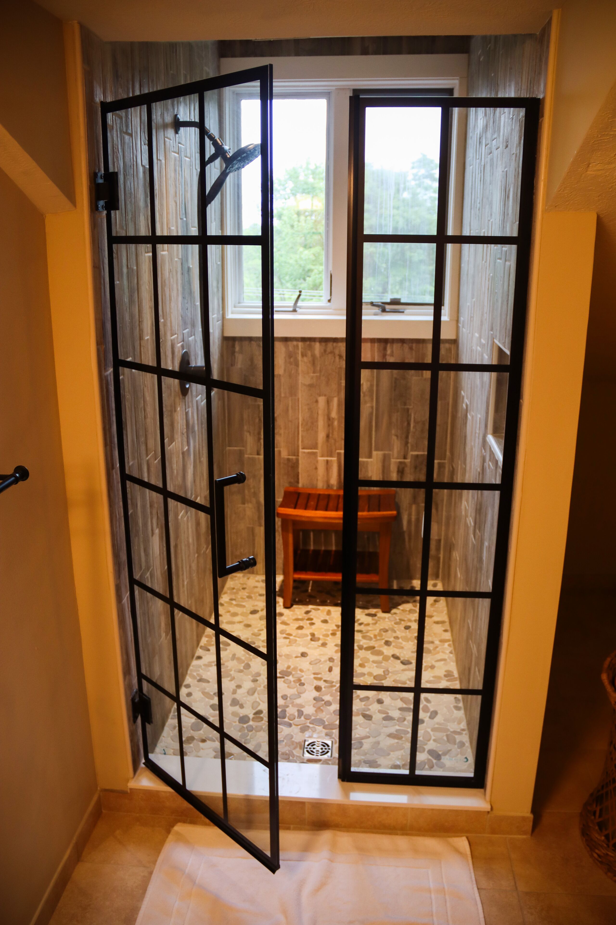 A room with a large window, a wooden bench, and a tiled floor.