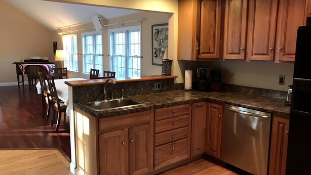 A kitchen with wooden cabinets, granite countertops, and a stainless steel dishwasher.