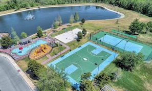 An aerial view of a park with a basketball court, playground, and a lake.