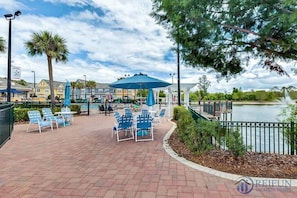 A waterfront patio with outdoor seating, a pool, and a view of the lake.