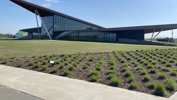 A modern building with a unique angular roof design, surrounded by a well-maintained grassy area. - Downtown Loft: King/Queen Suites- 2½ Baths  Near Convention Center EV charging (Fort Smith)