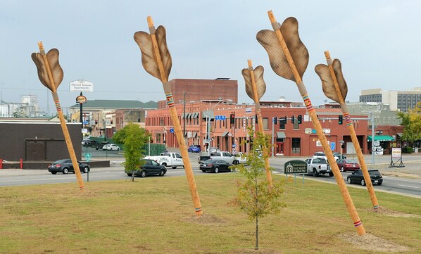 Une vue de rue avec, au premier plan, une rangée de sculptures en bois aux formes originales.
