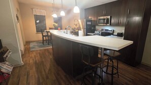 A modern kitchen with dark wood cabinets, a white countertop, stainless steel appliances, and pendant lighting. - Downtown Loft: King/Queen Suites- 2½ Baths  Near Convention Center EV charging (Fort Smith)