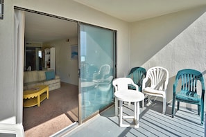Ein Balkon mit einer Schiebetür zu einem Wohnbereich mit einer Couch und einem Couchtisch.