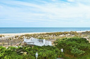 Une vue sur la côte, avec une plage, un bâtiment blanc doté d’une terrasse et une végétation luxuriante.