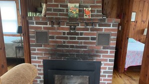 A brick fireplace with a black surround, wooden flooring, and a bench.