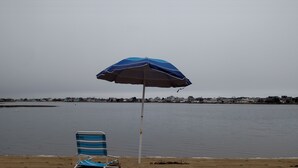 A beach with a striped beach chair and a blue and white umbrella.