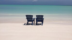 Dos sillas mirando hacia una playa con agua turquesa cristalina.