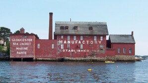 A red industrial building with a sign reading "Gloucester Sea Jacket Marine Paints" and "Manufacturer Established 1890".