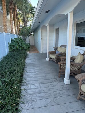 A covered patio with wicker furniture and a white brick wall.