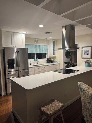 A modern kitchen with white cabinetry, stainless steel appliances, and a central island.