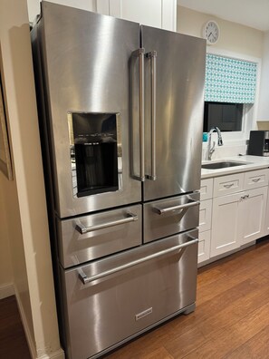 A stainless steel refrigerator with a built-in ice maker, a microwave, and a freezer drawer.
