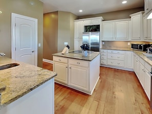 A kitchen with white cabinetry, a stainless steel refrigerator, and a granite countertop.