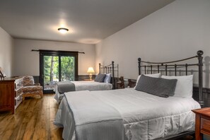 A bedroom with two beds, a wooden dresser, a nightstand, and a window with a view of trees. - *Rare Find* Mark Twain Lodge by MVL - Luxury Cabin with Hot Tub - EZ Cancel (Steamboat Springs)
