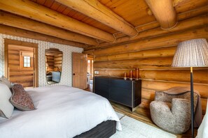 Ein Schlafzimmer in einer Blockhütte mit Bett, Schminktisch und Lampe.