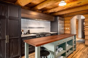 Eine moderne Küche mit dunklen Holzschränken, einer Marmor-Spritzschutzwand und einer Holztheke mit Sitzgelegenheiten.
