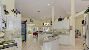 A spacious kitchen with white cabinetry, granite countertops, and a central island.
