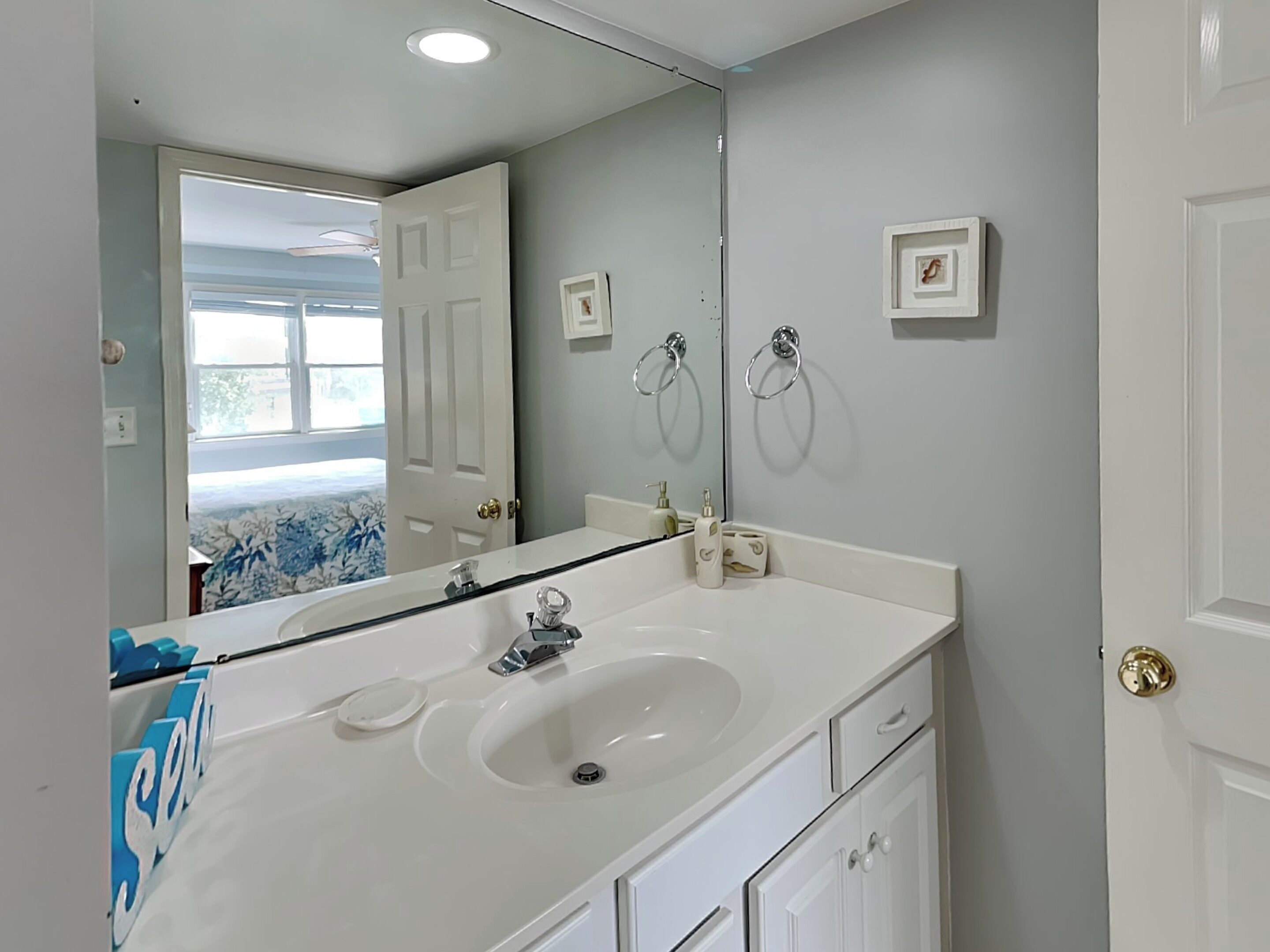 Une salle de bain avec un lavabo blanc, un miroir et une porte.