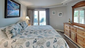 Une chambre à coucher avec un lit, une commode, un tableau et un balcon.
