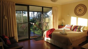 A bedroom with a bed, a chair, a nightstand, and a window with curtains. - ABSOLUTE Mollymook BEACHFRONT- Direct beach access  and views / Wifi / Smart TV  (Mollymook Beach)