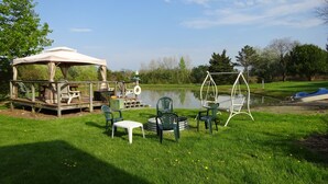 A gazebo with outdoor furniture, a swing set, and a pond in a park. -  Rest and relax- great view of Hemlock hills and surrounding area.  (Hemlock)