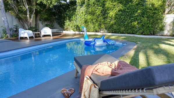 A swimming pool with lounge chairs and an inflatable swan float.