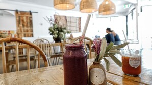 Een restaurantinterieur met houten tafels, stoelen en hangende lampen.