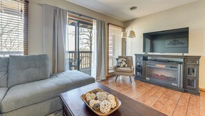 A living room with a grey sofa, a wooden coffee table with decorative balls, a fireplace, and a television. - 2 Mi to Silver Dollar City: Condo in Branson West (Reeds Spring)