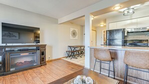 A modern kitchen with a built-in oven, a dining area with a wooden table and chairs, and a fireplace with decorative balls. - 2 Mi to Silver Dollar City: Condo in Branson West (Reeds Spring)