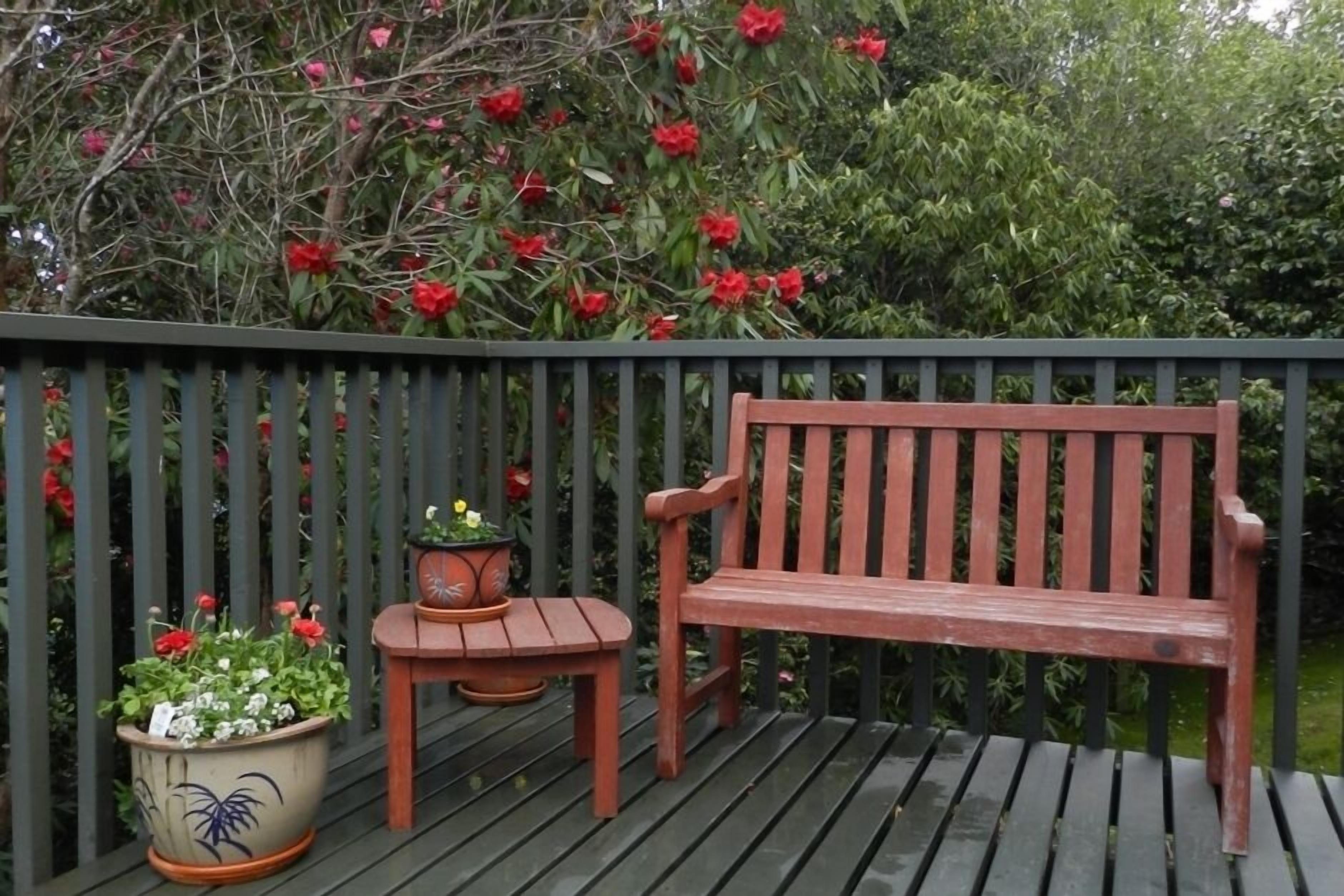 A wooden deck with a bench and a small table, surrounded by a black railing.