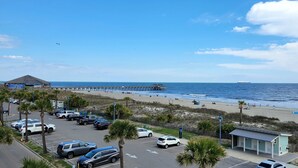 Vista de la playa con muelle, aparcamiento y un pequeño edificio.