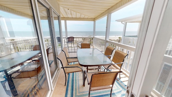 Enjoy ocean views from this covered outdoor space with a table and chairs.