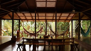 A spacious room with a high ceiling, wooden beams, and large windows offering a view of lush greenery outside. - Las Casas Costa Rica a private lodge in the Caribbean jungle (Cocles)