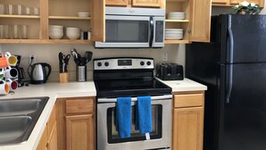 A kitchen with wooden cabinets, a stainless steel stove, a black refrigerator, and a microwave. - Lovely 2 King Size Ensuite BR , 3 Mi to Disney, 1min to Pool, Free WiFi &Parking (Kissimmee)