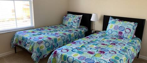 A bedroom with two beds, a nightstand, a lamp, and a framed picture on the wall.
