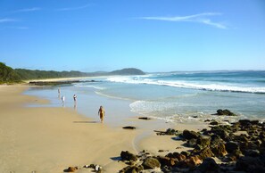 A beach with a sandy shore, rocky outcrops, and a clear blue sky. - Bannister Blu (Mollymook)