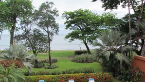 Zona junto a la piscina con sillones de descanso, vista al mar y jardín ajardinado con diversas plantas.