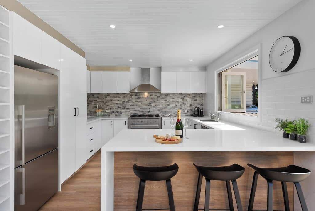 A modern kitchen with a central island, stainless steel appliances, and a large window.