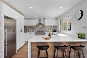 A modern kitchen with a central island, stainless steel appliances, and a large window.