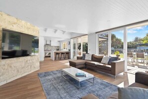 A modern living room with a stone accent wall, a large window, and a view of the outdoors.