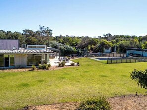 A modern house with a large lawn, a patio, and a fenced backyard.