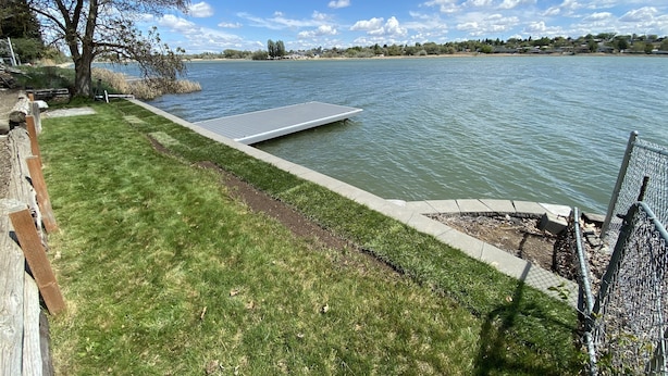 Une propriété située au bord d’un lac, dotée d’une pelouse, d’un quai et d’une clôture.