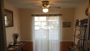 A dining area with a table, chairs, a ceiling fan, and a glass cabinet with bottles. - Cozy and Charming Condo in Naples (Naples)
