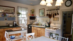 Una cocina con armarios de madera, estufa y una mesa de comedor con sillas.