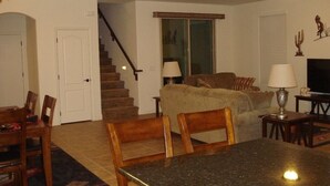 Ein Wohnzimmer mit Esstisch, Stühlen, einer Couch und einem Fernseher.